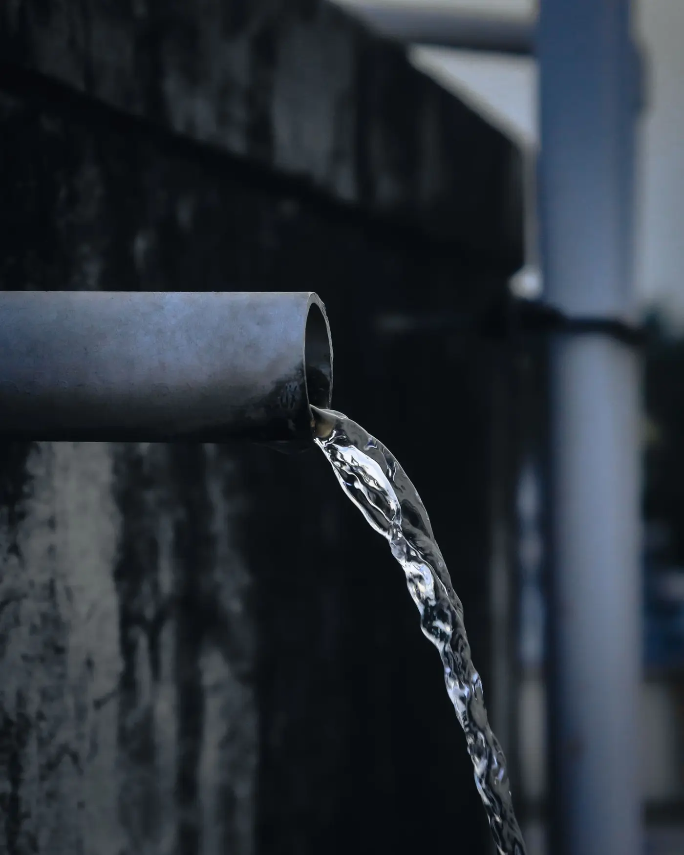 A hard stream of water blasting out of the open end of a metal pipe