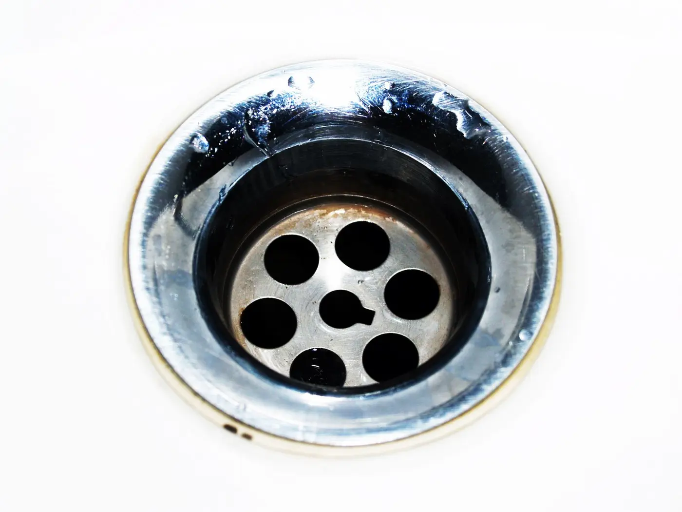 Close view of a stainless steel sink drain opening and strainer basket